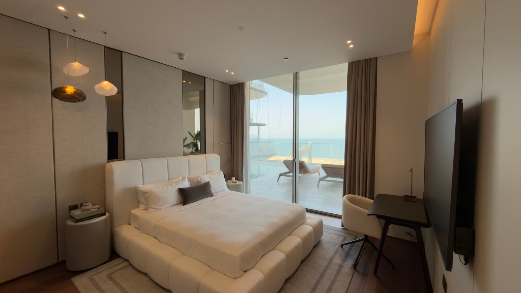 A bedroom opening onto the terrace, with loungers and the sea beyond
